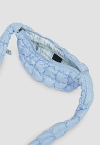 Helles blau gestepptes Bag mit einer strukturierten Oberfläche, ausgestattet mit einem Reißverschluss und einem gestreiften Innenfutter.