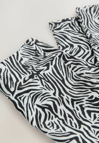 Crno-bijele tajice s uzorkom zebre, izrađene od mekog materijala s glatkom teksturom i urednim šavovima.