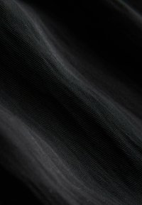 Svart texturerat tyg med subtila krusningar. Materialet verkar mjukt och lätt, med ett fint vävmönster över hela ytan.