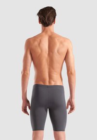 Graue, enganliegende Sportshorts aus glattem Stoff, die bis zur Mitte des Oberschenkels reichen und einen einfachen, elastischen Bund haben.