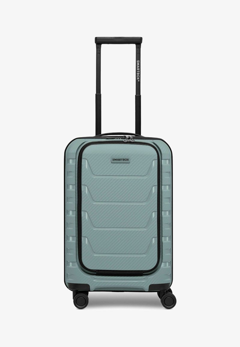 Valise rigide bleu clair avec poche zippée à l'avant, poignée noire extensible, quatre roues, et logo "SMARTBOX" centré sur le devant.