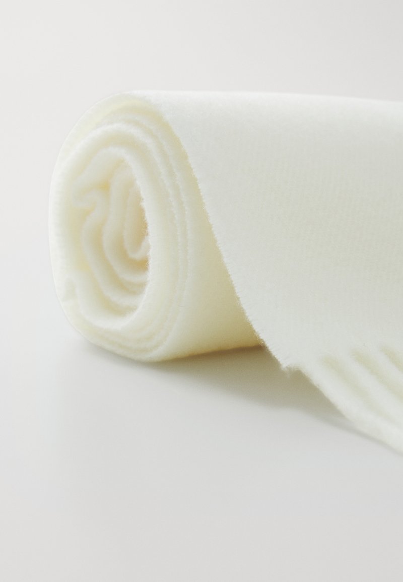 Couverture roulée de couleur crème, fabriquée à partir d'un tissu doux, avec une texture lisse et des bords soigneusement finis.