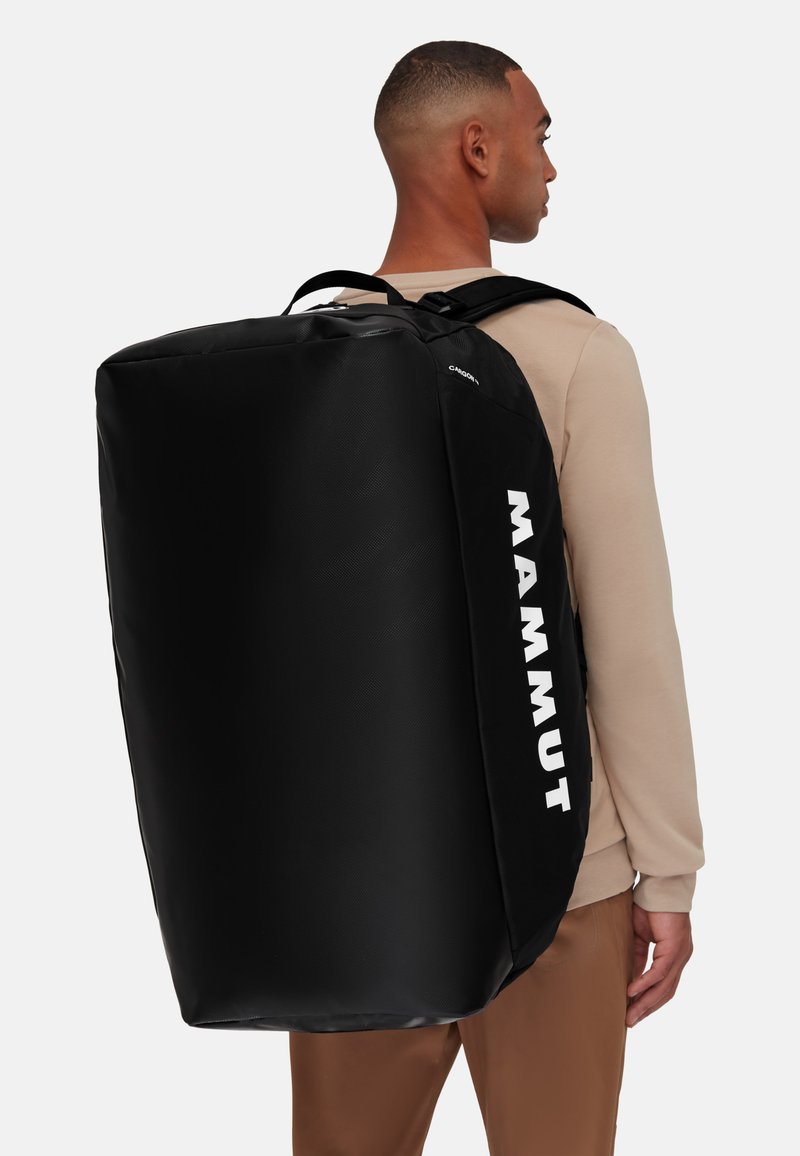Borsa nera di forma rettangolare, realizzata in materiale testurizzato. Presenta il logo bianco "MAMMUT" sul lato, spallacci regolabili.