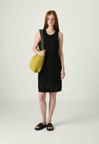 Vestido de malha preto sem mangas com um padrão texturizado, combinado com uma bolsa amarela plissada e sandálias pretas de tiras. Design simples e moderno.