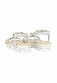 Sandali in argento intrecciati con una fascetta testurizzata, una soletta di un leggero color tannato e una suola piatta bianca con accenti argentati e un design rigato.