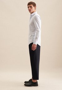 Camicia a maniche lunghe a righe bianche, pantaloni neri su misura e scarpe nere. Tessuto liscio, colletto classico e design slim fit.