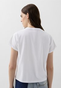 Witte T-shirt met korte mouwen, een ronde hals en een relaxte pasvorm. De stof lijkt lichtgewicht en zacht. Voorzien van opgerolde mouwuiteinden.