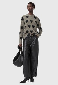 Maglione lavorato a maglia di colore grigio chiaro con motivi a cuore neri, abbinato a pantaloni in pelle nera a vita alta e una borsa nera. Stivali neri a punta.