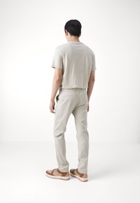 Light gray short-sleeve shirt, light gray pants, and brown sneakers. Soft texture, casual fit, clean lines, subtle design.
