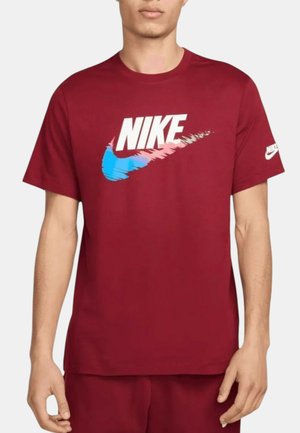 Camiseta de algodón roja con un gran logo de Nike en blanco y azul en un estilo dinámico. Mangas cortas con detalle del logo en la manga izquierda.