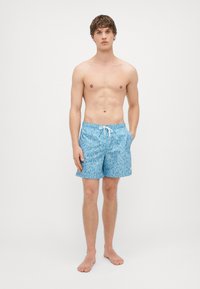 Sinised ujumispüksid reljeefse mustriga, millel on köitega vöökoht, kaks külgtaskut ja väike logo allääres.