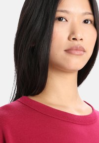 Sudadera roja de cuello redondo con textura suave, que presenta un cuello acanalado. La tela parece ligera y ligeramente ajustada en los hombros.