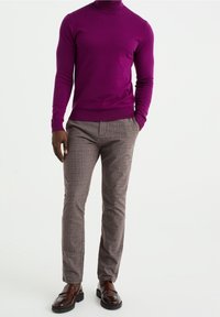 Pull à col roulé violet, ajusté. Pantalon marron à carreaux avec une texture subtile. Mocassins marron, finition lisse. Ensemble simple et moderne.