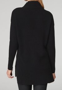 Svart stickad tröja med hög ribbad krage, långa ärmar, sidoflikar och en strukturerad nederdel för komfort och värme.