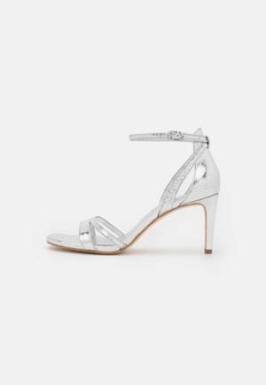 Silver high-heel sandal with an adjustable ankle strap, crossed front straps, and textured snakeskin pattern, featuring a tapered heel.