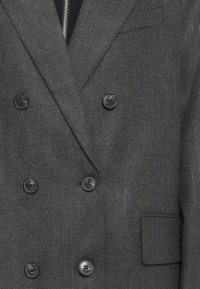 Blazer doppiopetto in tessuto di lana grigio scuro, con bottoni neri, taschino sul petto e fodera nera a contrasto con una cerniera.