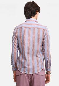 Camisa a rayas en azul claro y rosa con cuello abotonado, tejido texturizado y mangas largas, que cuenta con un dobladillo curvado y puños abotonados.