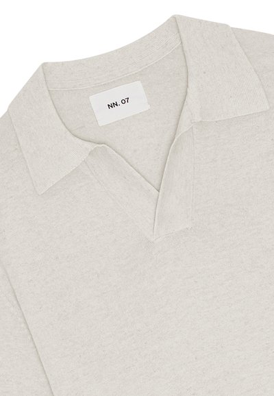 Maglione beige chiaro in maglia con collo ampio e scollo a V, con un'etichetta bianca con la scritta "NN.07" all'interno del collo.