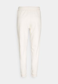 Kermavirta collegehousut, joissa on sileä pinta, joustava vyötärö ja kapenevat lahkeet, joissa on ribbireunukset nilkoissa.