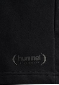 Zwarte sportkleding met een gestructureerde stof en een tonale grijze logo "hummel". Naaidetails zichtbaar langs de randen.