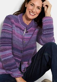 Strickjacke in Lila- und Violetttönen mit einem strukturierten Muster, featuring einen hohen Kragen und fünf großen Knöpfen.