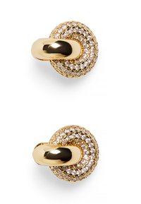 Guldtonad knapp med en texturerad yta och rund form, prydd med klara kristaller, och har en polerad guldring för fäste.