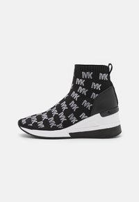 Schwarzer Sockenschuh mit weißem "MK"-Textmuster, dicker weißer Mittelsohle, schwarzem Fersenpanel und Zuglasche auf einem schlichten Hintergrund.