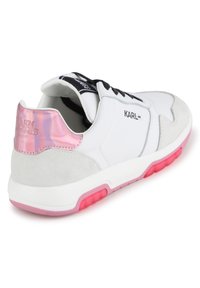 Λευκό αθλητικό παπούτσι με ροζ λεπτομέρειες και ανακλαστικό τακούνι. Διαθέτει ένα μείγμα από λείο δέρμα και σουέντ υφές, μαύρες κορδόνες και καουτσούκ σόλα.