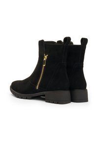 Pair of black suede ankle boots with gold side zippers and chunky rubber soles, shown from a rear angle on a white background.