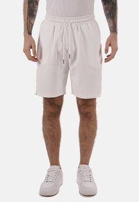 Pantaloni corti da uomo bianchi con cintura elastica e chiusura con lacci, realizzati in tessuto leggero. Texture liscia, design fino alle ginocchia.