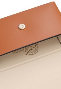 Borsetta in pelle marrone con chiusura a scatto dorato. L'interno è foderato in crema con dettagli in rilievo "Pelle Vera Made in Italy".