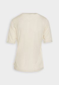 Kortærmet cremet t-shirt med en afslappet pasform, rund halsudskæring og blød struktur. Har en lille detalje nær bunden.