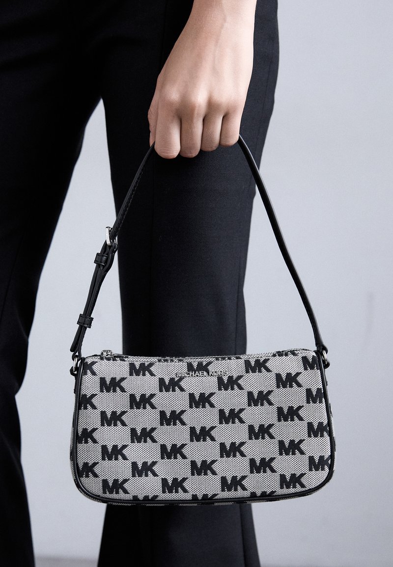 Black and gray canvas handbag featuring repeated "MK" logo pattern, slim design, and a short black shoulder strap. Zipper closure at top.