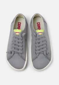 Sneakers in tela grigia con design a stringhe, suole in gomma bianca e una soletta vivace gialla e rossa con il logo "CAMPPER".