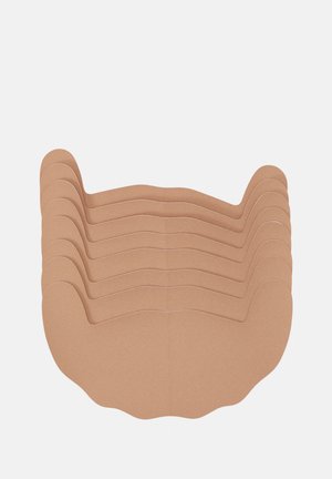 Stapeltje van zes beige, zelfklevende tepelcovers met afgeronde, gekartelde randen op een witte achtergrond.