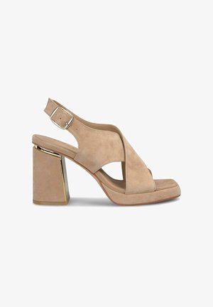 Tacón slingback de ante beige con punta cuadrada, diseño entrecruzado y un robusto tacón bloque con detalles metálicos. Correa ajustable en el tobillo.