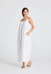 Rochie maxi albă fără mâneci, cu un guler plissetat, buzunare laterale și un croi lejer, confecționată dintr-un material ușor.