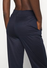 Marineblauwe broek van zachte stof, met een elastische tailleband en een achterzak. Het ontwerp is losjes passend en casual.