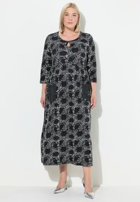 Vestido impreso en blanco y negro con mangas tres cuartos, escote redondo con detalle de ojal y bolsillos laterales.