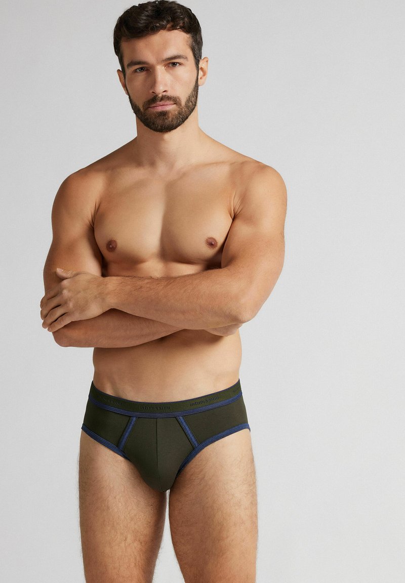 Ciemnozielone figi z niebieskimi akcentami, charakteryzujące się dopasowanym krojem i gładką fakturą. Pasek w talii jest markowy i stylizowany z kontrastowym wykończeniem.