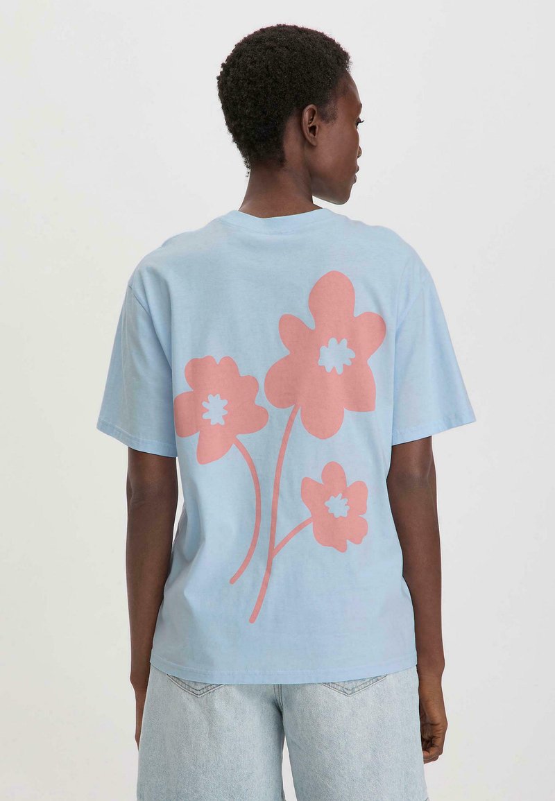 Blauwe T-shirt met korte mouwen, voorzien van grote roze bloemgraphics op de achterkant. Gemaakt van zacht materiaal met een relaxte pasvorm en een ronde hals.
