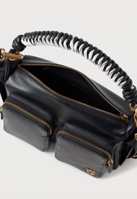 Μαύρη δερμάτινη τσάντα χειρός με συρμάτινη μαύρη και λευκή λαβή, δύο μπροστινές τσέπες με φερμουάρ και χρυσές μεταλλικές λεπτομέρειες.