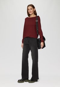 Bordeauxkleurig longsleeve shirt, zwarte wijde jeans, zwarte tas met een schouderband en chunky zwarte laarzen met olijfgroene zolen. Eenvoudig, textuurontwerp.