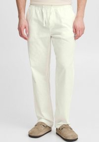 Lichtgekleurde linnen broek met een elastische tailleband en een koord, voorzien van zijzakken en een relaxte pasvorm. Zachte textuur en losse vorm.