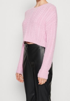 Rosa kort tröja med texturerad kabelstickad design, med långa ärmar och ett mjukt, fluffigt material. Matchad med svarta, figurnära byxor.