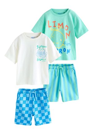 Dve súpravy pre batoľatá s krátkymi rukávmi a šortkami; jedno biele tričko s potlačou palaciniek, modré kockované šortky; jedno tyrkysové tričko s potlačou citrónov, pruhované šortky.