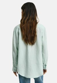 Lichtgroene, lange mouwen shirt van linnen, met een gebogen zoom en knoopmanchetten, met een relaxte pasvorm en minimale textuurdetails.