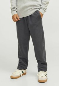 Grå fleece joggerbyxor med sidfickor och elastisk midja, ihop med krämfärgade sneakers med gröna detaljer och gummisula.