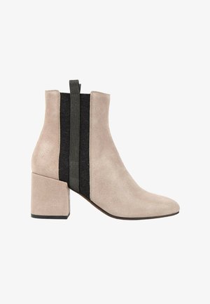 Bottine en daim beige avec talon bloc, côtés élastiques noirs et languette en tissu à l'arrière pour un enfilage facile.