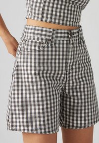 Bruna och vita rutig shorts med en åtsittande midja, framfickor och rak ben-design. Tillverkade av vävt tyg med en strukturerad känsla.